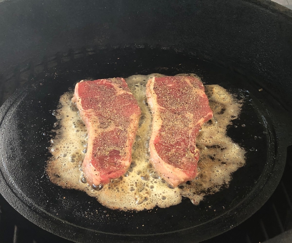 Cooks steaks in garlic butter