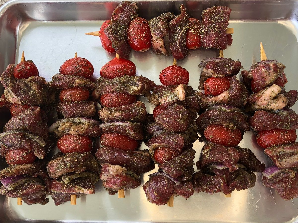 Thread skewers by alternating lamb cubes with tomatoes and onions