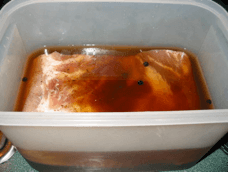 Pork belly submerged snugly in non-reactive brining container